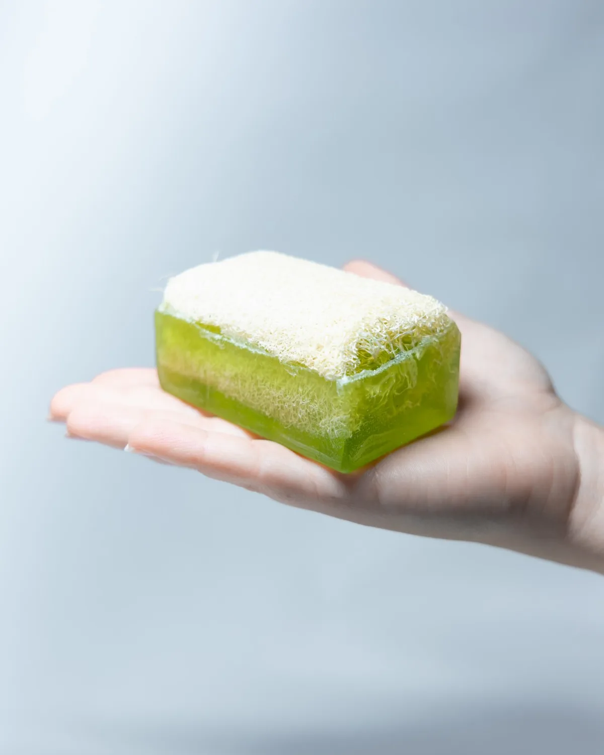 Un savon Rosée posé dans une main ouverte, face luffa vers le haut